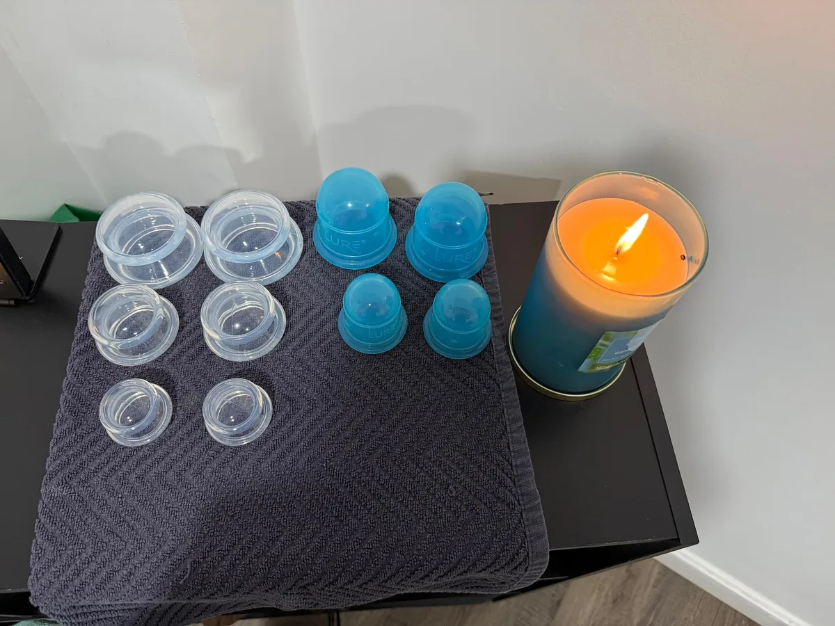 Clear and blue silicone cupping cups laid out on a towel beside a lit candle
