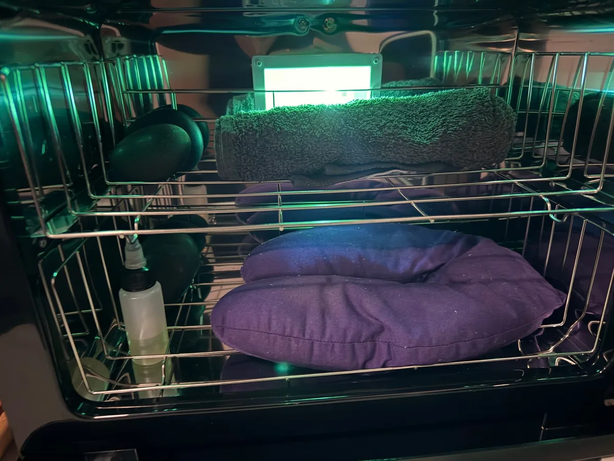 Hot cabinet holding rolled towels, warm packs and basalt stones under a green light